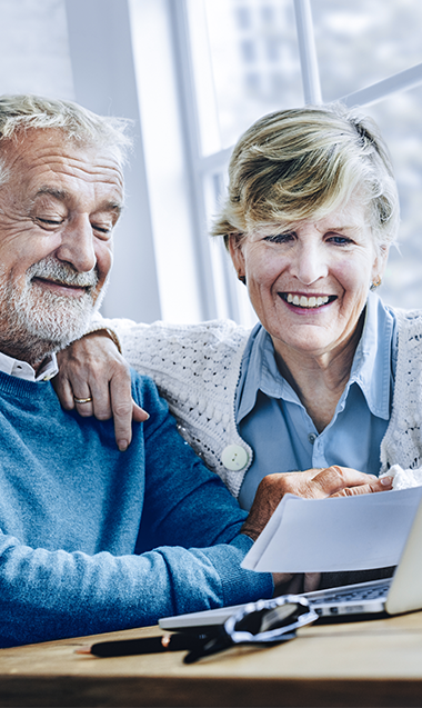 Older couple looking at notes in front of their desktop
